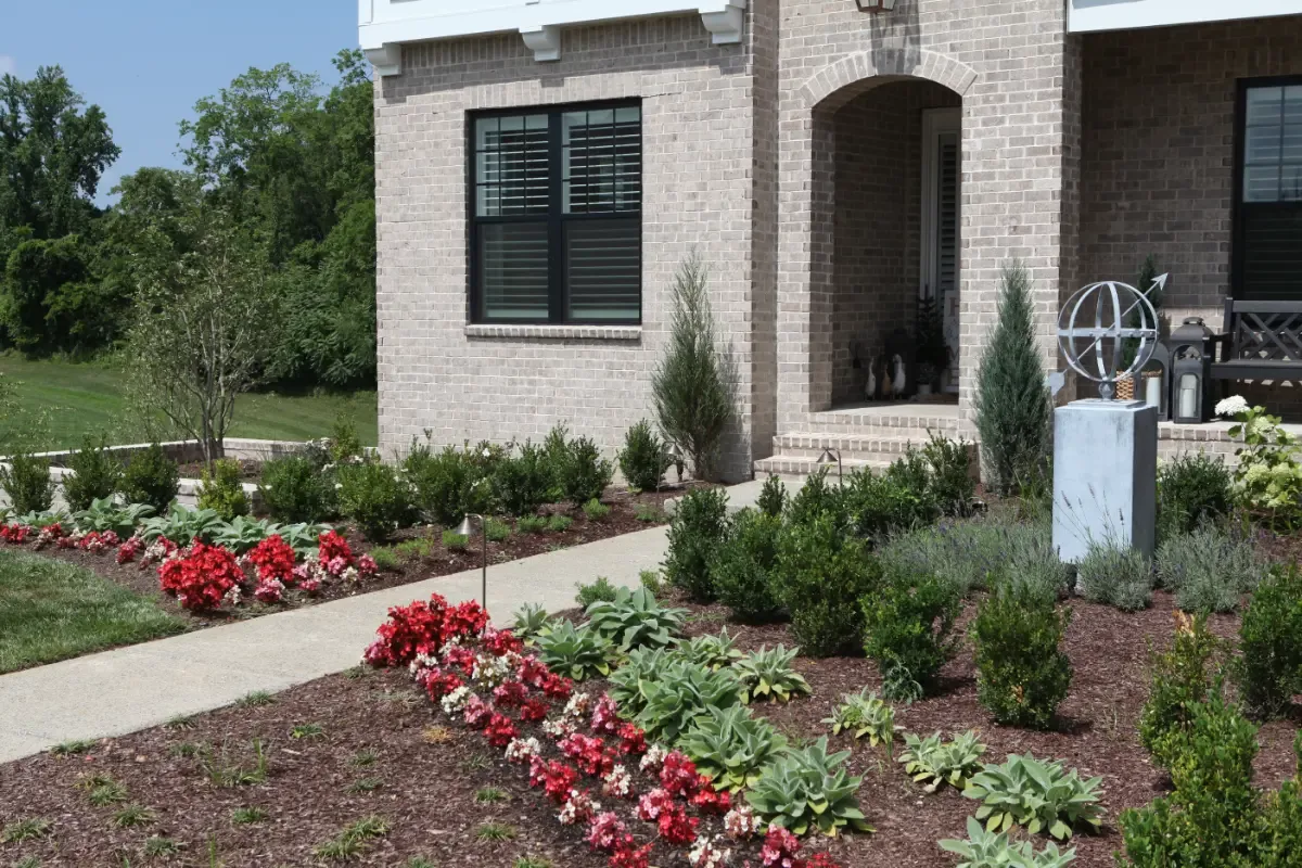 A brick home with annual flower beds along the front walk