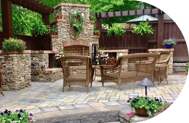 A stone outdoor kitchen with wicker seating
